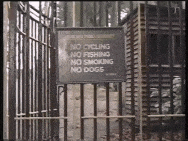a sign on a fence says no cycling no fishing no smoking no dogs