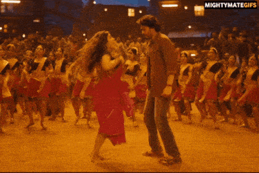 a man and a woman are dancing in front of a crowd with the words mightymategifs on the bottom right