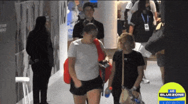 a group of people are walking down a hallway with a bluezone sign in the background