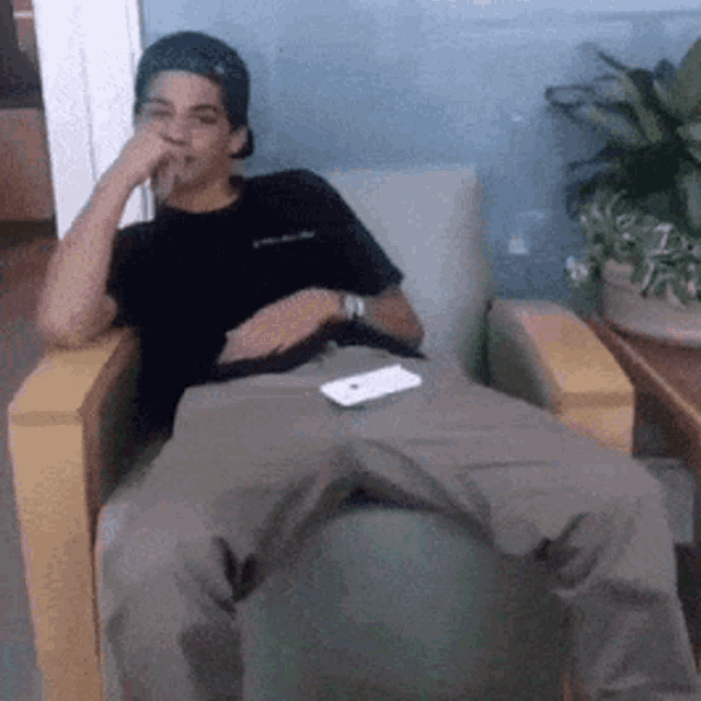 a man is sitting in a chair with his legs crossed and a cell phone on his lap .