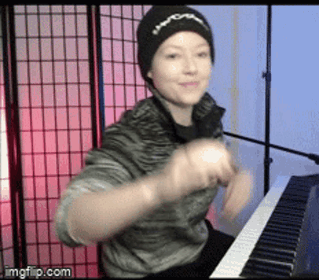 a woman wearing a beanie is playing the piano