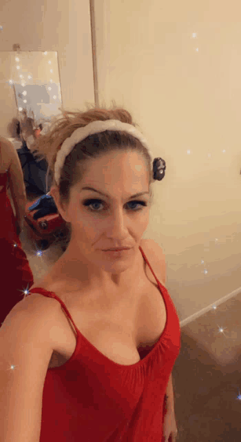 a woman in a red tank top is taking a selfie