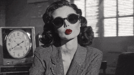 a black and white photo of a woman wearing sunglasses and red lipstick .