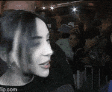 a woman is standing in front of a crowd of people and talking to someone .