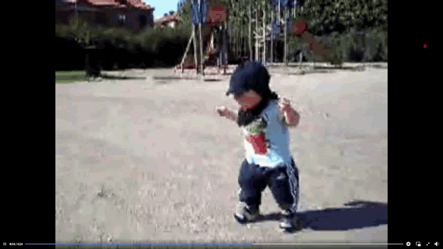 a little boy wearing a hat is walking in a dirt field