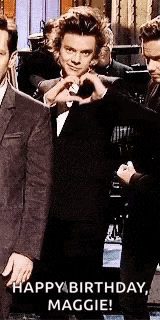 a man in a tuxedo is making a heart shape with his hands while standing next to another man .