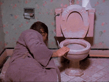 a man in a purple robe is vomiting in a pink toilet