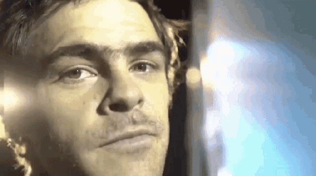 a close up of a man 's face in a dark room with a light shining on it .
