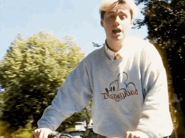 a man is wearing a disneyland sweatshirt