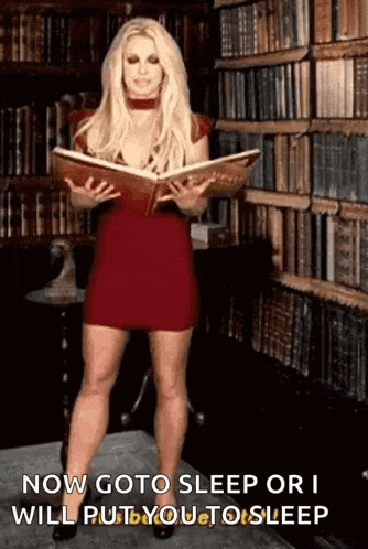 a woman in a red dress is standing in a library holding a book .