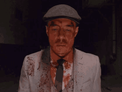 a man in a white suit and tie with blood on his face