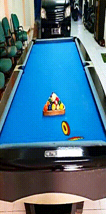 a pool table with balls on it and a car parked behind it