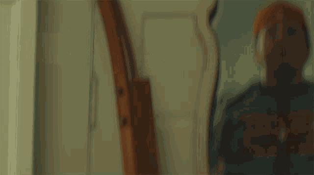 a blurry picture of a man in a hat looking at himself in a mirror .
