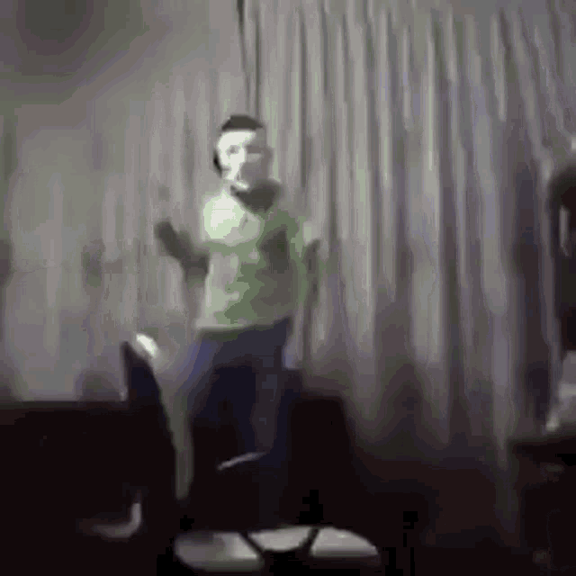 a man wearing a mask is dancing in a living room while sitting on a chair .