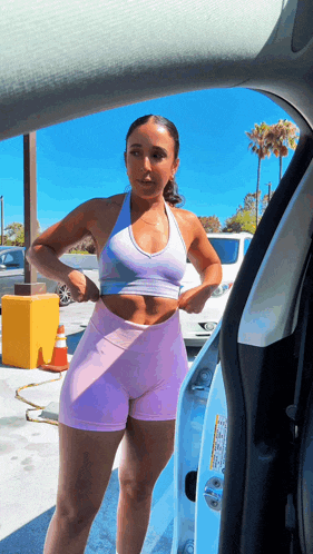 a woman in a sports bra and shorts is standing in a car