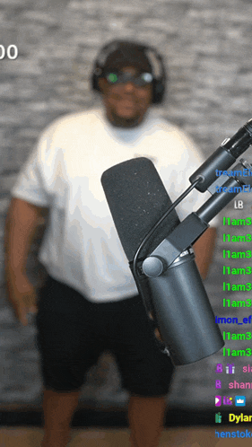 a man wearing headphones stands in front of a microphone with the number 00 on the bottom left