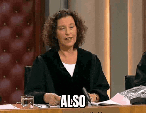 a woman is sitting at a table with a microphone and a glass of water .
