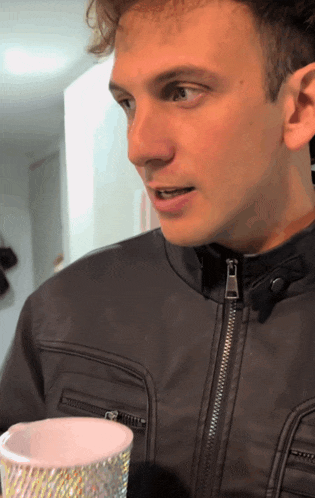 a man in a black leather jacket is holding a cup