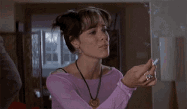 a woman in a purple sweater and necklace is holding something in her hands