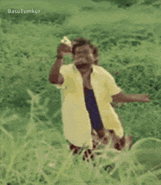 a man in a yellow shirt is standing in a grassy field