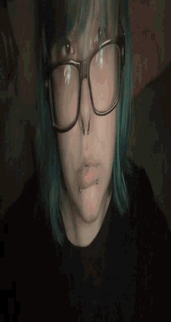 a woman with blue hair is wearing glasses and piercings on her face