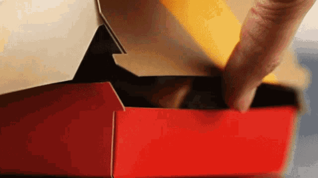 a close up of a person 's hand opening a red box
