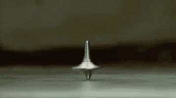 a silver spinning top is spinning on a table in a dark room .