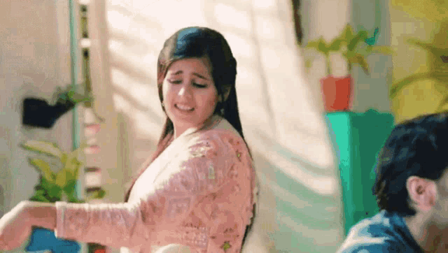 a woman in a pink dress is dancing in front of a man in a blue shirt