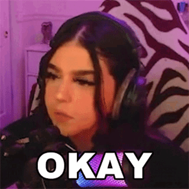 a girl wearing headphones is sitting in front of a microphone and the word okay is written on the screen .
