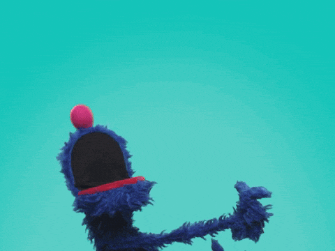 a blue sesame street character giving a thumbs up with his mouth open