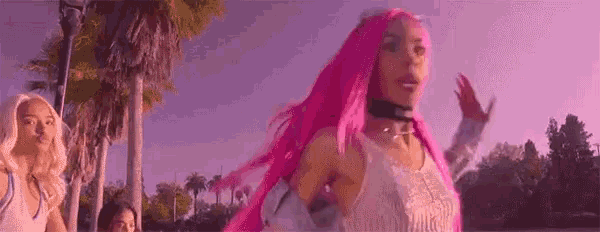 a woman with pink hair and a choker is walking down a street .
