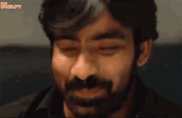 a close up of a man 's face with his eyes closed and a beard .