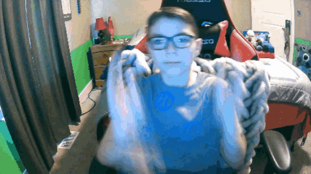 a boy wearing glasses is sitting in a room with a chair that says xbox on the back