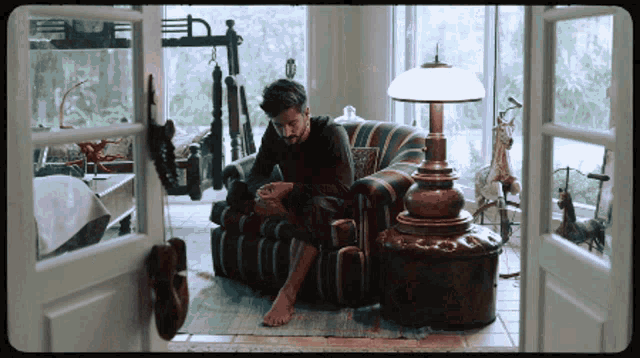 a man sits in a chair in a living room with a lamp