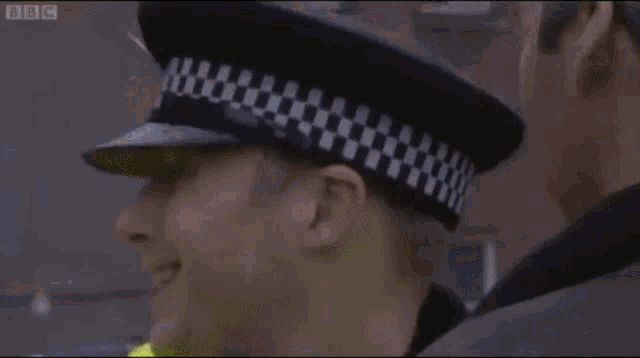 a police officer is yelling at another man while wearing a hat and a yellow jacket .