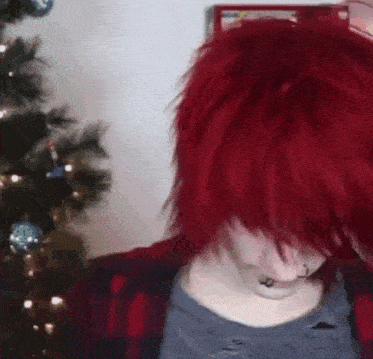 a girl with red hair is sitting in front of a christmas tree .