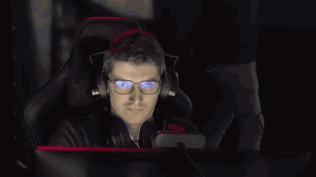 a man wearing headphones and glasses is looking at a computer monitor
