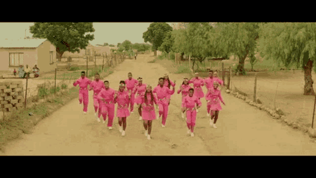 a group of people running down a dirt road