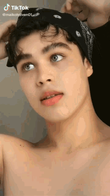 a young man without a shirt is wearing a bandana on his head ..