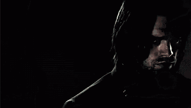 a man with long hair and a beard is wearing a black jacket and looking at the camera .