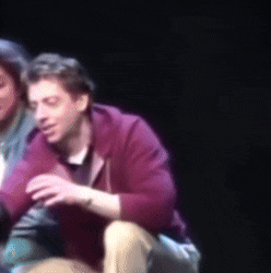 a man in a red hoodie sits next to a woman in a green shirt