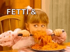 a little girl is sitting at a table eating spaghetti with a fork .