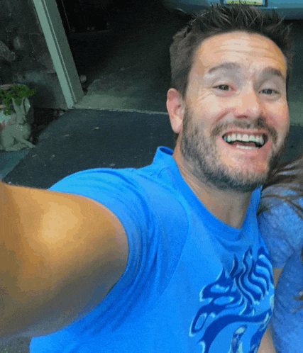 a man in a blue shirt is smiling and taking a picture