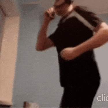 a man in a black shirt is talking on a cell phone while dancing .