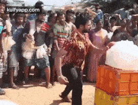 a man is standing in front of a crowd of people while holding a bucket of ice .