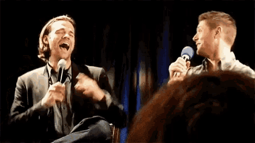 two men are sitting in front of microphones on a stage .