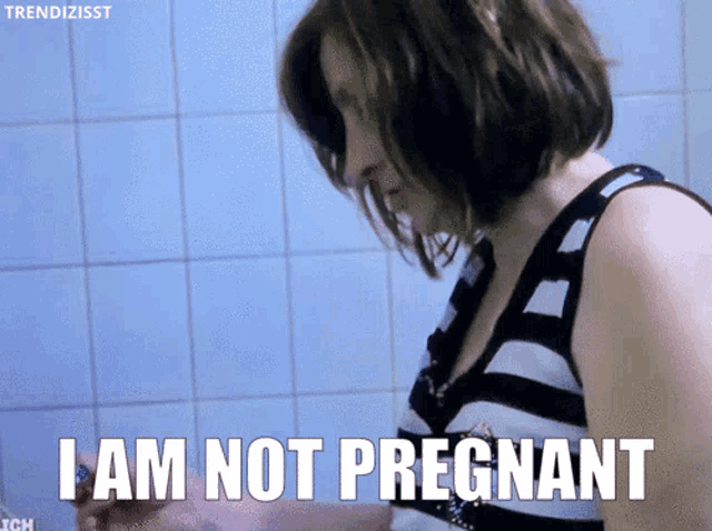 a woman says i am not pregnant while standing in a bathroom