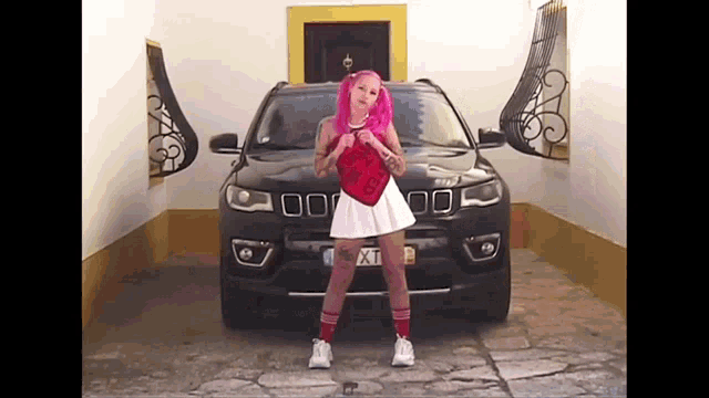 a woman with pink hair is standing in front of a jeep with the license plate xt