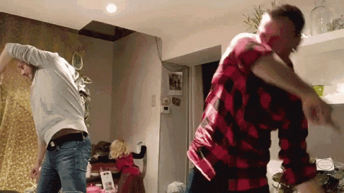 two men in plaid shirts are dancing in a kitchen