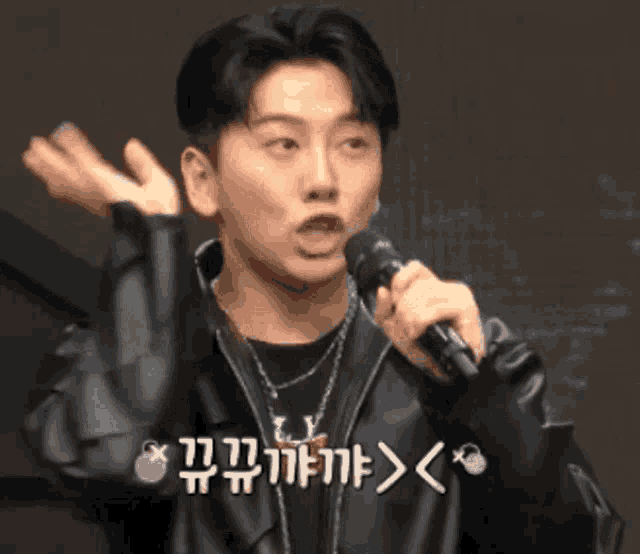 a man in a leather jacket is holding a microphone in his hand